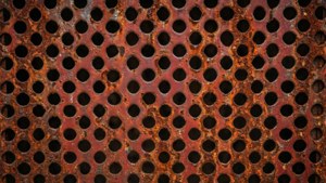 Gealterte rostige perforierte Metallstruktur mit unregelmäßigen Löchern für eine Vintage-Industrie-Ästhetik.
