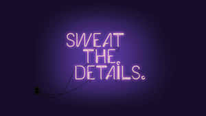Pink neon sign saying 'SWEAT THE DETAILS' on a dark purple wall.