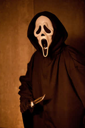 Een gemaskerd horrorfiguur in een zwarte mantel die een mes vasthoudt in een slecht verlichte kamer. — Halloween Maskers Achtergronden