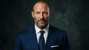 Mark Strong poserer i en skarp marineblå dress med intenst blikk, filmatisk portrett.
