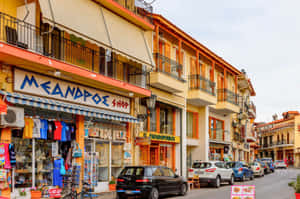 Colorful shops and parked cars line a sunny urban street. — Delphi Picture