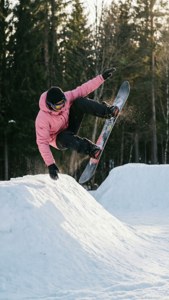 Snowboarder udfører en frontside 180 fra en sidehit i en skovrydning.