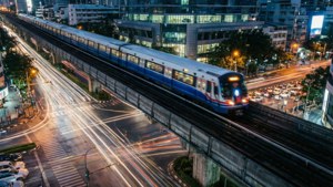 Larga exposición del BTS Skytrain y estelas de luz de tráfico nocturno.