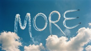 Sebuah pesawat skywriting mengeja 'MORE' dengan asap di langit biru cerah.
