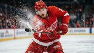 An action shot of a Red Wings player taking a slapshot with ice spray.