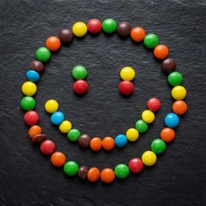 Ylhäältä kuvattu asettelu, jossa Smarties on järjestetty hymiöksi liuskekivellä.