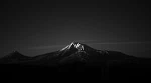 Snow-capped mountain peak glowing at dusk above a dark city skyline. — Minimalist Design Picture