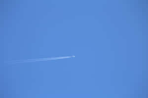 Ett litet flygplan flyger högt på en klarblå himmel och lämnar två vita kondensstrimmor. — Solid Dark Blue Bakgrundsbilder