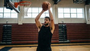 JJ Redick practicing jumpshots in an empty gym with natural light.