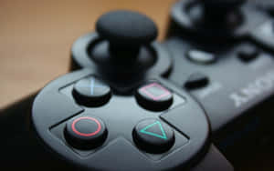 Närbild av en svart PlayStation-kontroll med glödande knappar på trä.