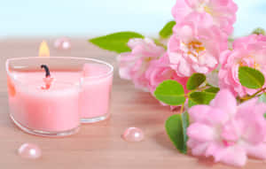 Rosa lys brenner ved siden av rosa roser og perleperler på tre.
