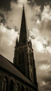 A tall stone church spire against a cloudy sky in sepia tones. — Church Background