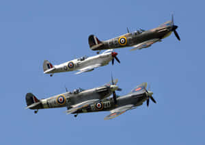 Three vintage fighter planes flying in formation against a clear blue sky.