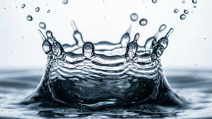 Makro-Nahaufnahme eines Wasser-Spritzers, der in der Zeit eingefroren ist und eine Kronenform bildet.