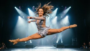 Brooke Hyland voert een split sprong uit op het podium in een zilveren pailletten kostuum onder schijnwerpers