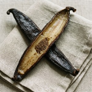 Open vanilla bean pod with seeds on linen.