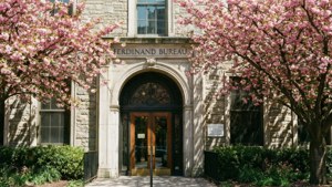 En lys og munter tapet af Ferdinand Bureau-bygningen omgivet af blomstrende kirsebærblomster.