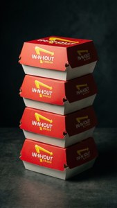 Fotografi makanan komersial dari kotak burger In-N-Out yang ditumpuk dengan pencahayaan samping yang dramatis