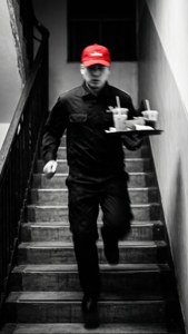 Een dramatische noir-opname van een bezorger die haastig de trap op rent.