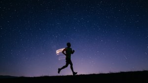 Siluet minimalis seorang pelari di bawah langit berbintang, membangkitkan mimpi dan tujuan.