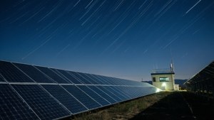 Foto malam dengan eksposur panjang dari pembangkit listrik tenaga surya di bawah jejak bintang