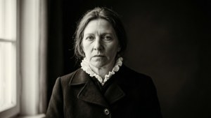 Et høy-kontrast monokromt portrett av Joan Homius med et alvorlig uttrykk.