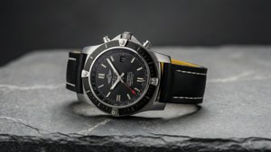 Minimalistisk sidevisning av Breitling-klokke på grå steinflate