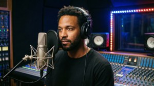 Nico Collins indspiller musik i et professionelt studie med hovedtelefoner og mikrofon.