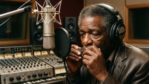 Sonny Boy Williamson II registra in uno studio vintage, concentrato sulla sua armonica.