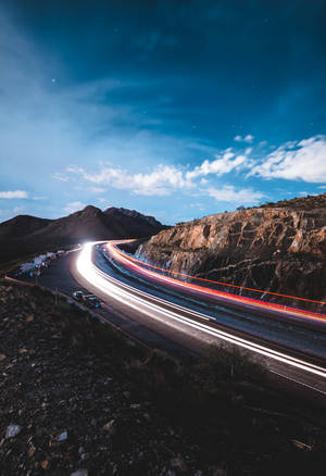 Long exposure of car lights on a mountain road at twilight with stars visible. — Road Wallpaper