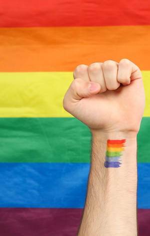 Raised fist with rainbow tattoo against rainbow flag background. — Subtle Lgbt Picture