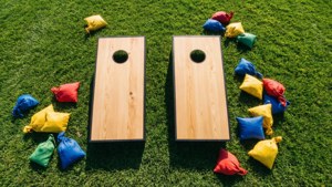Cena de verão clara vista de cima com tábuas de cornhole paralelas e sacos de feijão coloridos.