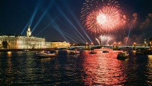 Scena notturna vivace sul fiume con ponte illuminato, fuochi d'artificio e barche festive