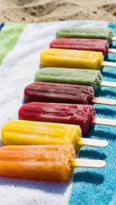 Colorful popsicles melting in the sun on a beach towel, summer vibe.