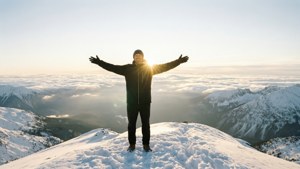 Charles Smith di puncak gunung bersalju saat matahari terbit dengan lembah berawan yang luas