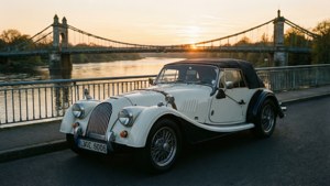 Morgan Plus Six en un puente al amanecer, río tranquilo.