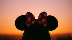 Silhueta do laço da Minnie Mouse contra um belo fundo gradiente de pôr do sol.