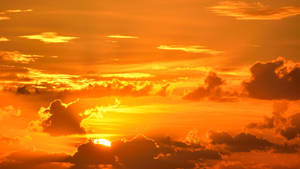 Zonsonderganglucht met oranje wolken en gloeiende zon achter wolken