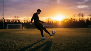 Soccer player kicking ball at sunset on grass field — Jake Moody Picture