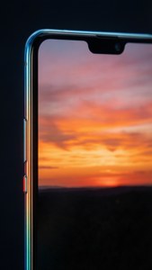 Huawei-telefon som reflekterar en färgstark solnedgång
