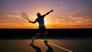 En silhuett av Stefan Edberg som serverer ved solnedgang, som skaper et kunstnerisk og dramatisk bakgrunnsbilde.