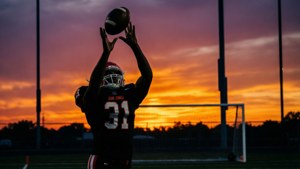 Silhueta de Jauan Jennings fazendo uma recepção ao pôr do sol.
