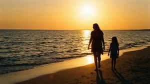Silhuetter af mor og datter ved solnedgangsstrand