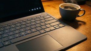 Wallpaper makro yang nyaman menampilkan keyboard Microsoft Surface Laptop Studio dengan kopi dan cahaya hangat.