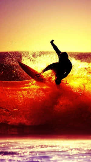 Surfare som rider på en våg vid solnedgång med livfulla orange och röda färger. — Surfing iPhone Bakgrundsbilder