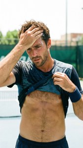 Marcel Granollers wiping sweat with his shirt during a match.