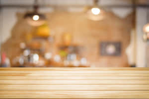 Wooden tabletop in a cozy cafe with blurred background lights and shelves. — Blur Effect Picture