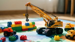 Eine Makroaufnahme eines Spielzeugkrans auf einer bunten Spielmatte mit Bauklötzen.