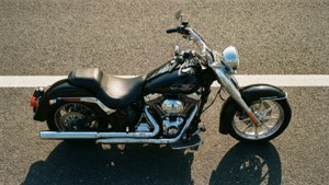Black motorcycle with chrome details parked on asphalt road in bright sunlight. — Chopper Motorcycle Picture