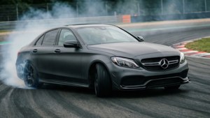 Matgrijze C300 die agressief driftt op een racebaan.